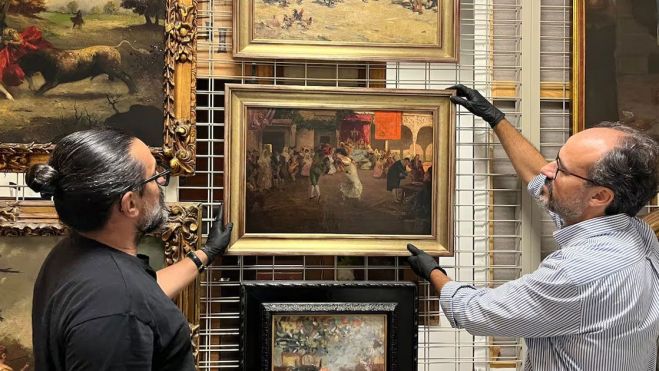 Dos conservadores de la Casa de Colón sostienen el cuadro incautado a Pedro Rico 'Cruz de mayo', de Eugenio Lucas, en una imagen facilitada por el Cabildo de Gran Canarias.