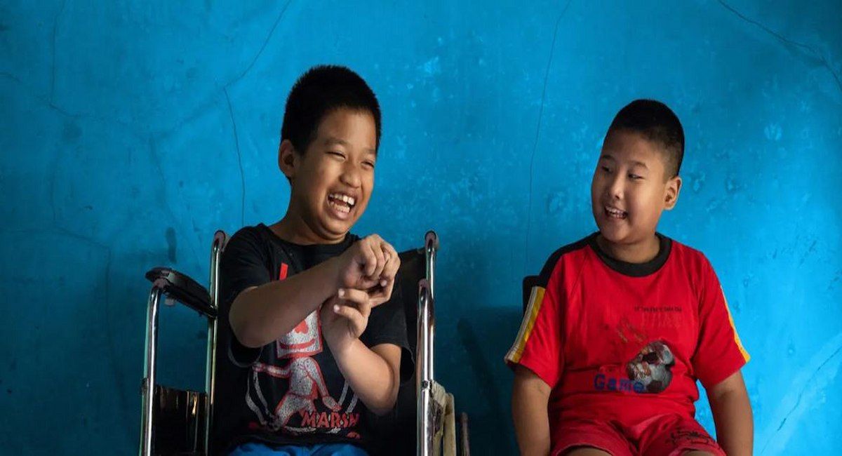 Un niño de 12 años con discapacidad física se sienta junto a su mejor amigo, un niño de 9 años con discapacidad visual, en Java Central, Indonesia. | Foto: UNICEF/Ijazah