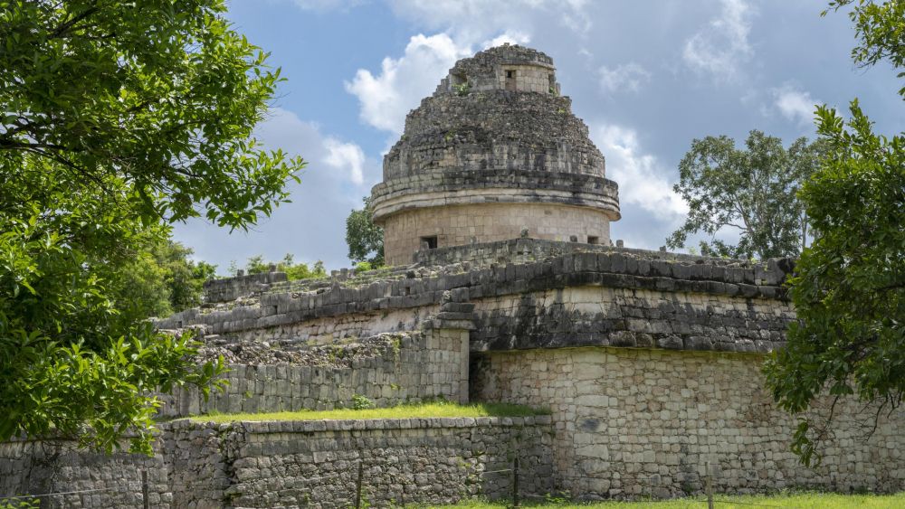 México Chichén Itzá El Caracol Observatorio vista desde el jardín mostrando la torre redonda y la plataforma inferior rodeada de árboles tropicales