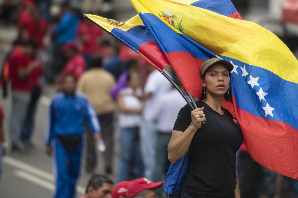 Una manifestante enarbola una bandera de Venezuela.